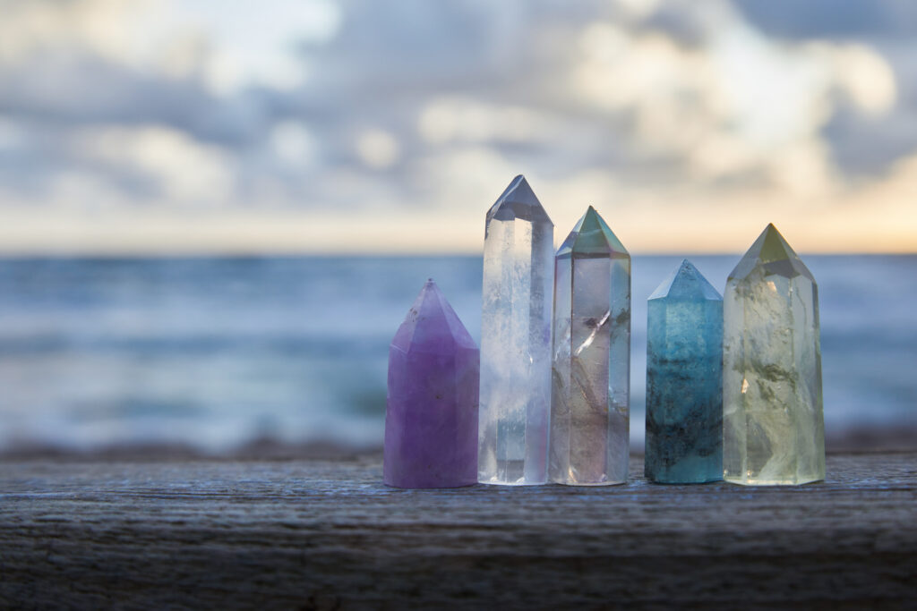 Healing Reiki Crystals on wood with sea at sunset background. Healing stones at the seaside
